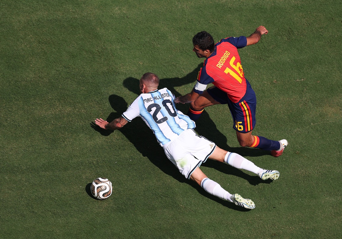 Alexis Mac Allister tumbles to the ground under pressure from Rodri