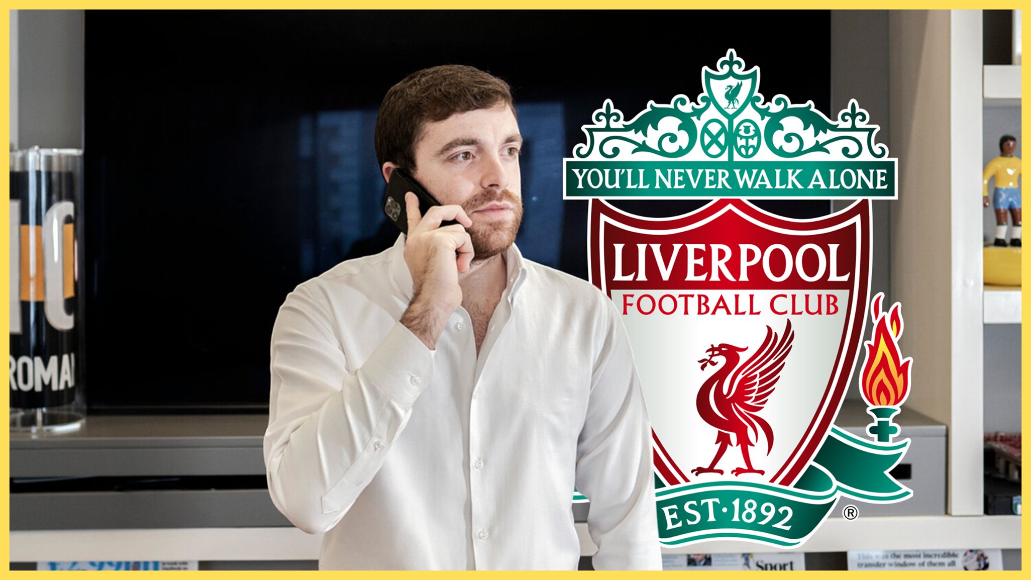 Transfer news expert Fabrizio Romano takes a phone call next to Liverpool club crest.