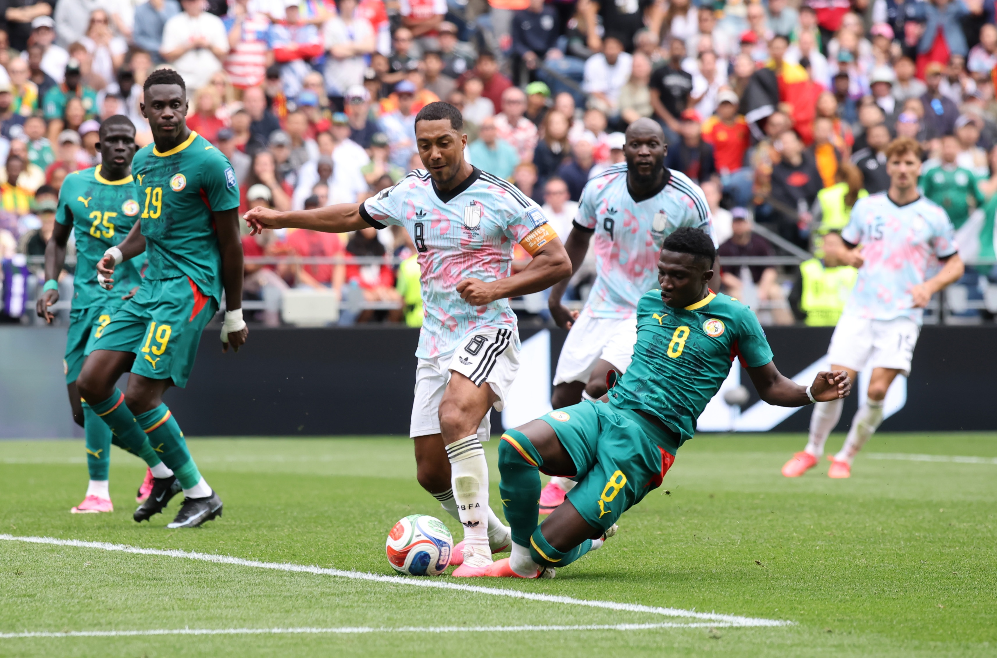 Lamine Camara slide tackles Youri Tielemans during World Cup game.